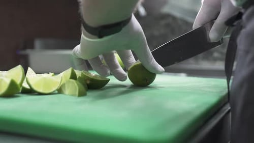 Chef Preparing Lime Slices with Knife on Board
