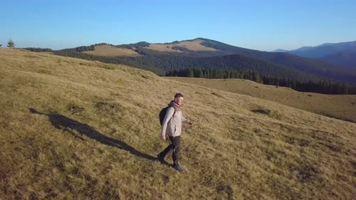 Man Hiking Grassy Mountain in Sunny Rural Landscape