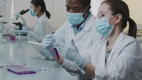 Slowmo von Wissenschaftlern, die Lösung im Reagenzglas inspizieren und posieren
