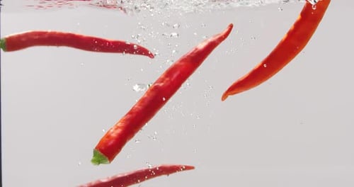 Red Chili Peppers Dropping Into Water