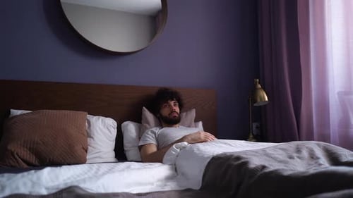 Man Waking Up and Stretching in Bed