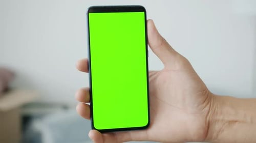 Closeup of Male Hand Holding Green Chroma Key Screen Smartphone Indoors
