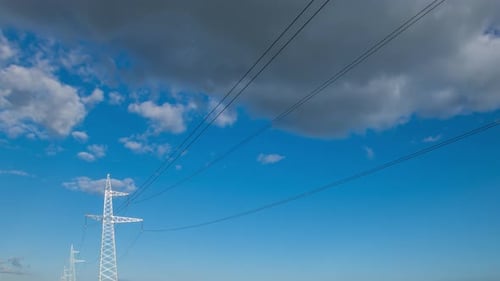 Weitwinkel-Stromübertragungsleitungen Hochspannungsnetz mit bewölktem blauem Himmel und Sonnenstrahlen