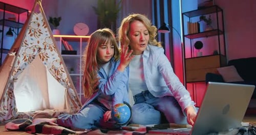 madre que pasa el ocio nocturno conjunto con una linda hija positiva en el suelo