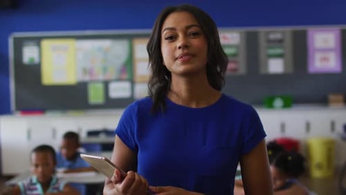 Smiling Teacher Holding Tablet in Classroom