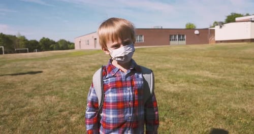 Little boy wearing a face mask walking to school