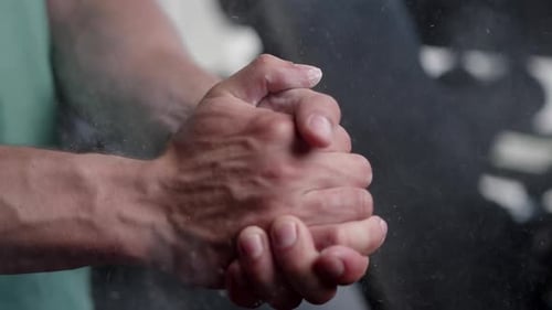 A man in a gym rubbing chalk over his hands with cotton while preparing for a workout