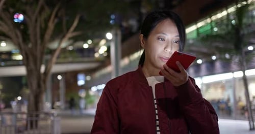 Frau benutzt nachts Handy in der Stadt