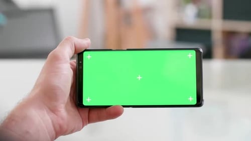 Man Hand Holding the Smartphone Horizontally with Green Screen on