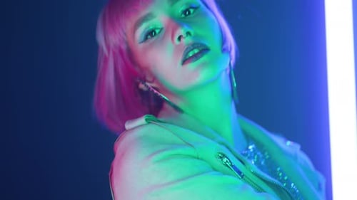 Portrait of Party Girl Dancing to the Music on Glowing Multicolored Lamps in Night Club
