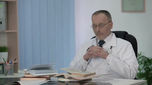 Doctor Reads Medical Books in Office