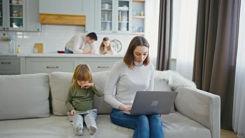 Young Mother Working on Laptop at Home Her Family Nearby Woman Looking at Window for Concentration