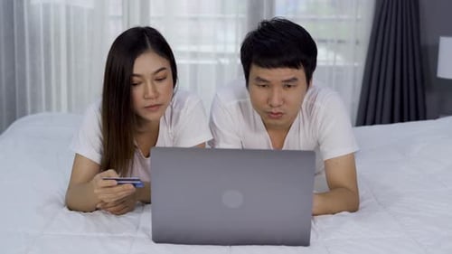 Couple Shopping Online with Laptop on Bed