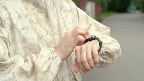 Man Interacts with Smart Watch Outdoors in Urban Setting