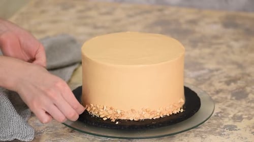 Baker Decorating a Cake with Nut Pieces Close Up