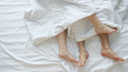 Couple's Feet Under Duvet in Bed, Overhead Shot