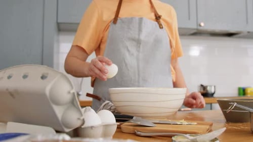 Woman Cracking an Egg into Bowl in Kitchen