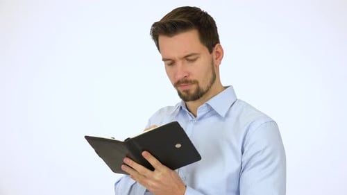 A Young Handsome Man Writes Into a Notebook - White Screen Studio
