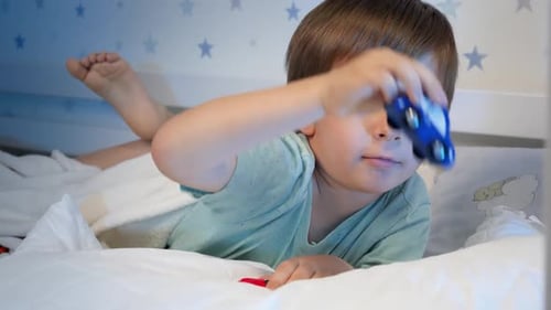 Boy Playing With Toy Car in Bed