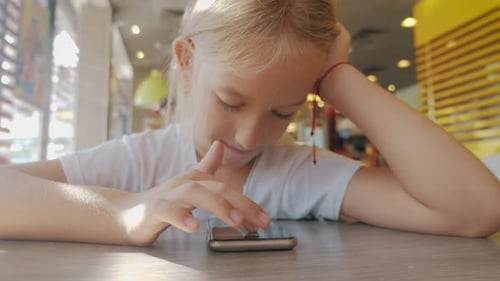 Happy Child Girl Look Smart Phone. Little Girl Play Mobile Phone. Education, School, Technology and