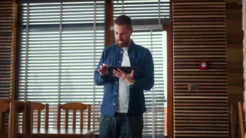 Man Uses Tablet Indoors by Window