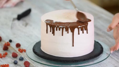Baker gießt flüssige Schokolade ein. Konditor-Bäcker verzieren große schöne Sahnetorte