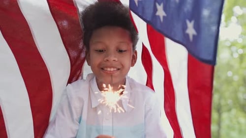 Child Smiles with Sparkler and American Flag