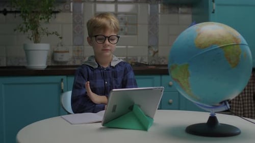 6 Years Old School Boy Studying Online Using Tablet Computer From Home