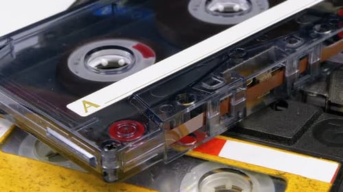 Three Vintage Audio Cassettes Rotate on White Background