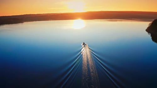 Aerial view of landscape during sunset. Camera follows the boat sailing on the river towards the sun