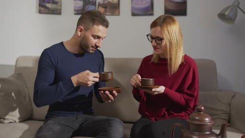 Couple Talking and Drinking Tea on a Couch