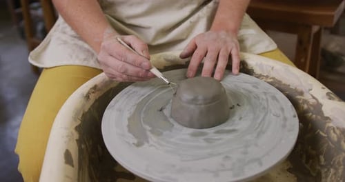 Section centrale d'une potière utilisant un outil à boucle pour la finition de la poterie dans un atelier de poterie