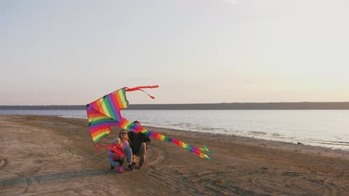 Family Flies Kite on Sandy Beach at Sunset