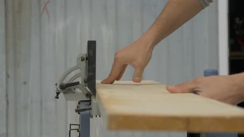 Man Using Jointer to Smooth Wood in Workshop