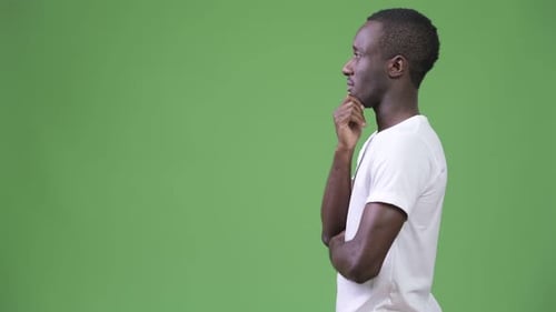 Profilansicht eines jungen afrikanischen Mannes, der vor grünem Hintergrund denkt