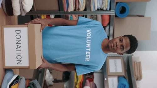 Portrait View of the Volunteer Man Holding Cupboard Box with Donation Word and Looking at the Camera