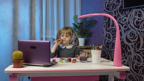 Child Paints at Desk with Laptop Indoors