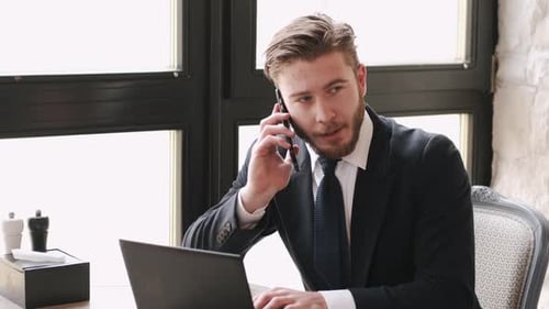 Focused Businessman Working at a Cafe with Laptop and Papers