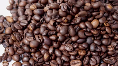 frisch geröstete Kaffeebohnen fallen aus der Packung auf den Tisch, ebene Oberfläche, gießen von oben nach unten. Sonnenstrahlen