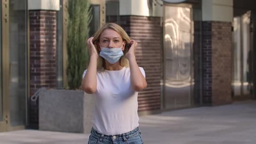 Young Woman Putting on Blue Protective Face Mask