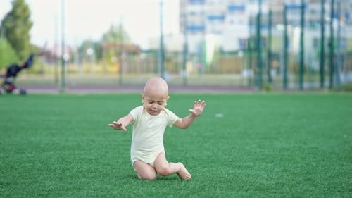Aufgeregter Kleinkind verliert das Gleichgewicht und fällt auf Gras