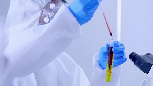 Científico en la suite de EPP investigando un líquido en un tubo de ensayo en LabolaBroom01774799 1