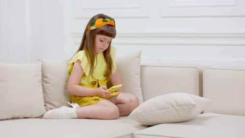 Girl Using a Smartphone on White Sofa