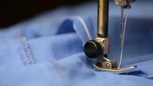 Nähmaschine näht blauen Stoff mit weißem Faden