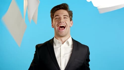 Businessman Throwing Papers Documents Into Air and Celebrates Success on Blue Studio Background