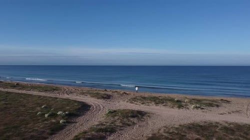 Lonely Traveler Goes on a Sandy Road Straight to the Sea