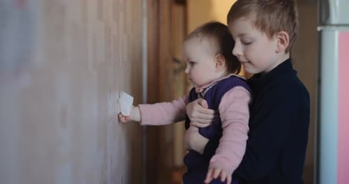 Cute Little Girl Washes the Wallpaper with Her Brother