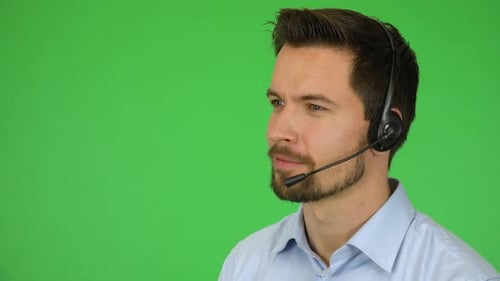 A Young Handsome Call Center Agent Talks To a Caller with a Smile - Closeup - Green Screen Studio