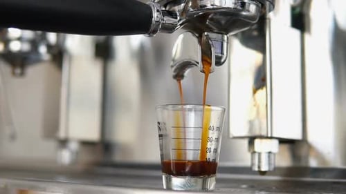 Espresso Extracting into Small Glass from Machine