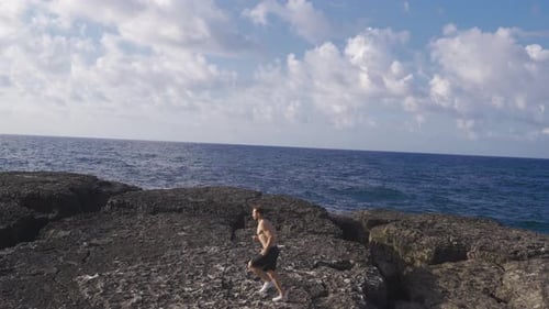 Man Runs Shirtless on Rocky Coastline by the Ocean